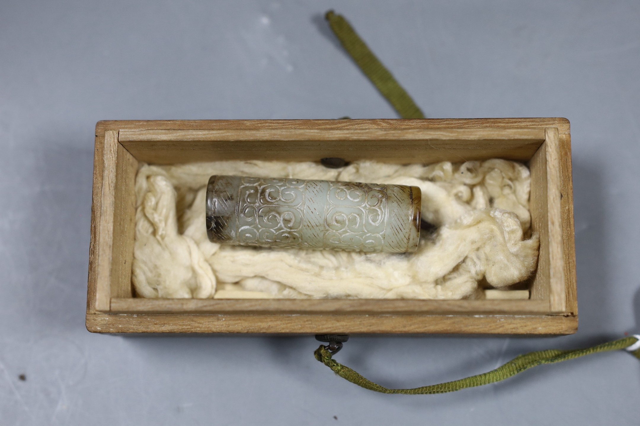 A Chinese archaistic white and black jade cylinder bead, 5.8 cm, boxed and a Chinese archaistic jade large bi disc, 13 cm diameter